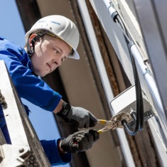 Techniker montiert eine Small Cell an der Hauswand